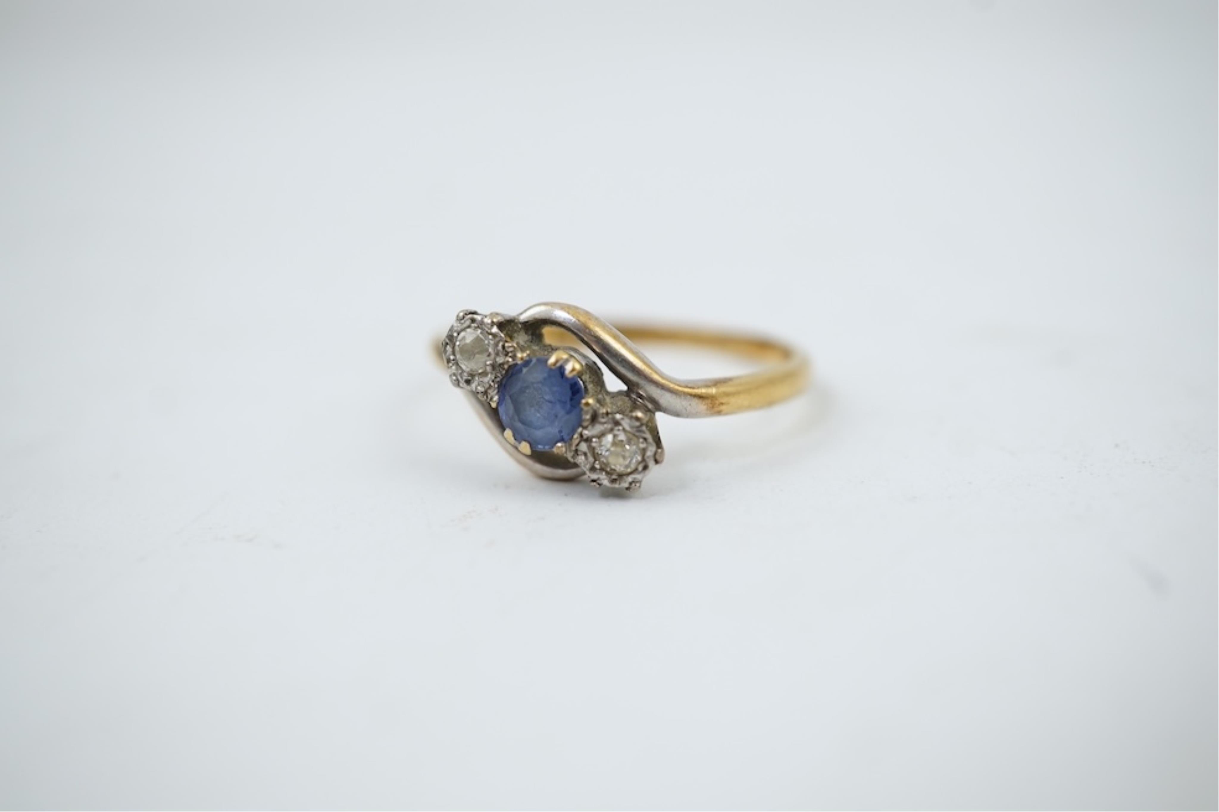An early 20th century 18ct gold, sapphire and diamond set three stone crossover ring, size P/Q, gross weight 2.4 grams.
